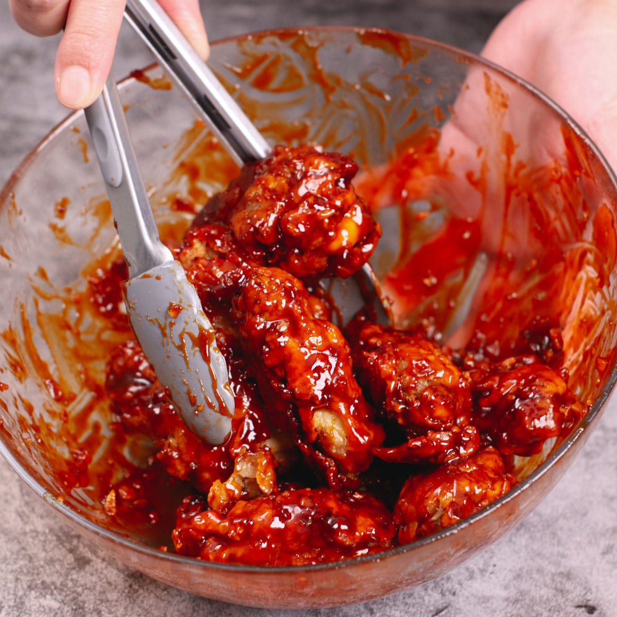 Coating Yangnyeom chicken wings with Korean spicy sauce.
