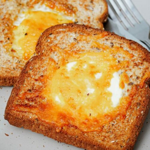 Air fried egg toasts, 2 slices, on a plate with fork and knife.