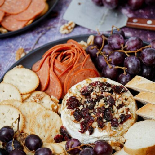 Air Fryer Baked Brie recipe bite shot, with baguette slices, grapes, crackers, and pepperoni.