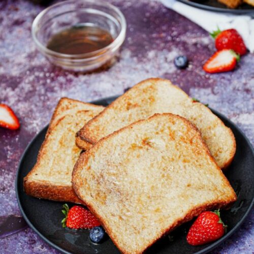 Air fryer French toast recipe bite shot served with berries and maple syrup.