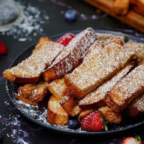 Air fryer French toast sticks recipe bite shot, served with caramel dipping sauce and berries.