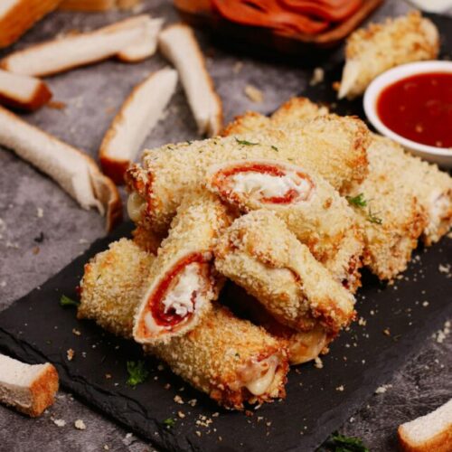 Air fryer pizza roll ups recipe bite shot, served on a black stone with pizza dipping sauce