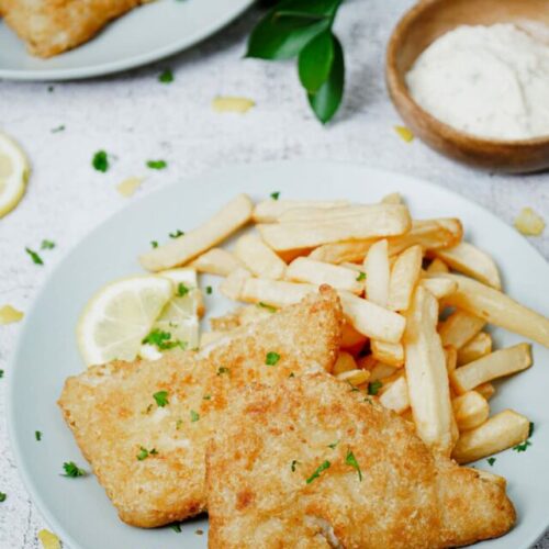 Cooked frozen air fryer fish and chips recipe bite shot, with lemon slices and tartar sauce.