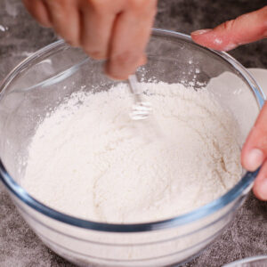 Mixing dry batter in a large glass bowl.