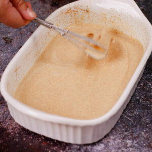 Mixing custard mixture in a shallow baking dish.