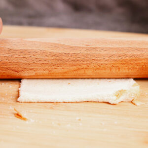 Step 1: Flattening the bread with a rolling pin.
