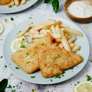 Cooked frozen air fryer fish and chips with lemon slices and tartar sauce.