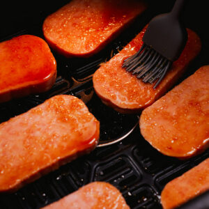 Glazing Spam slices with a basting brush.
