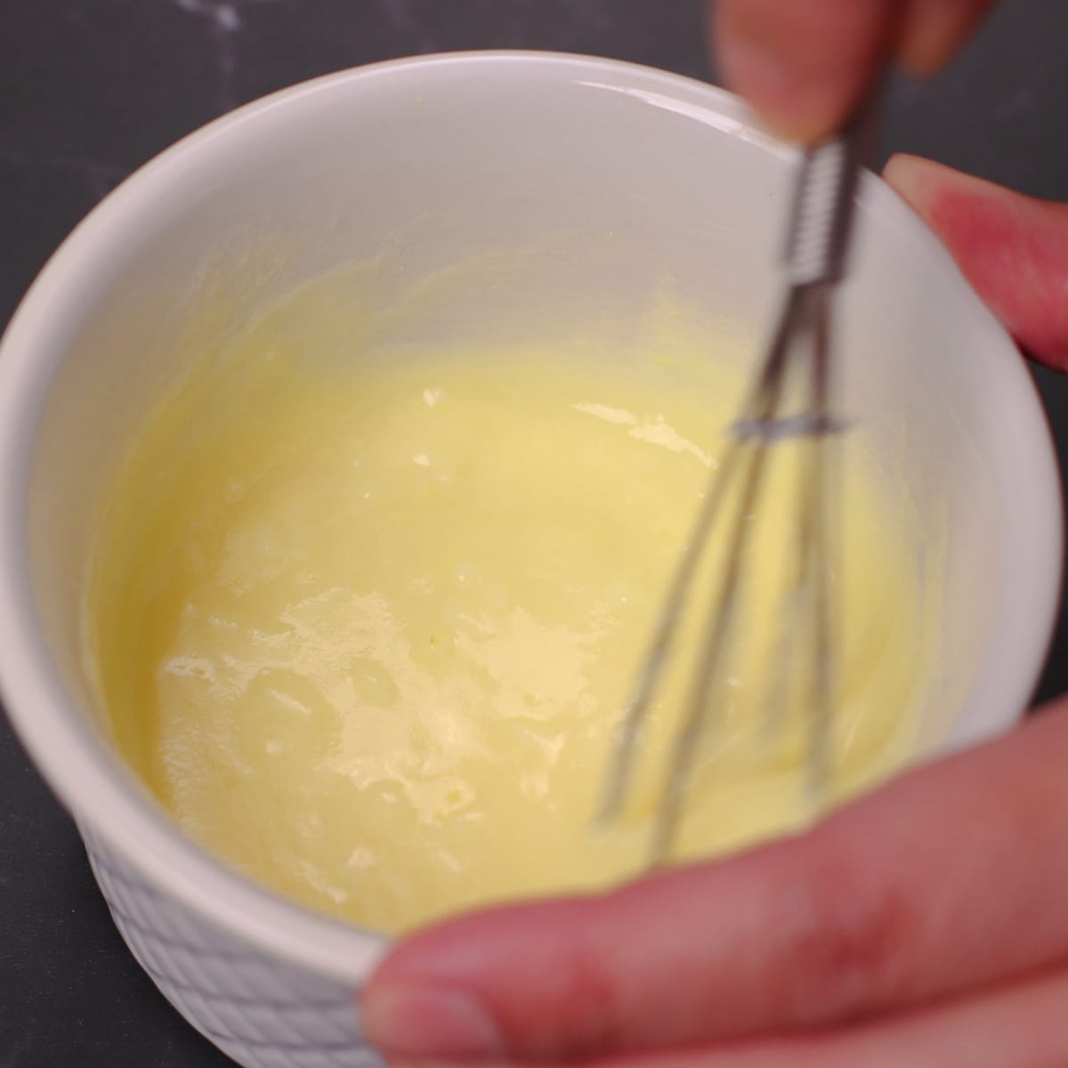 Mixing lemon garlic butter sauce in a ramekin bowl.