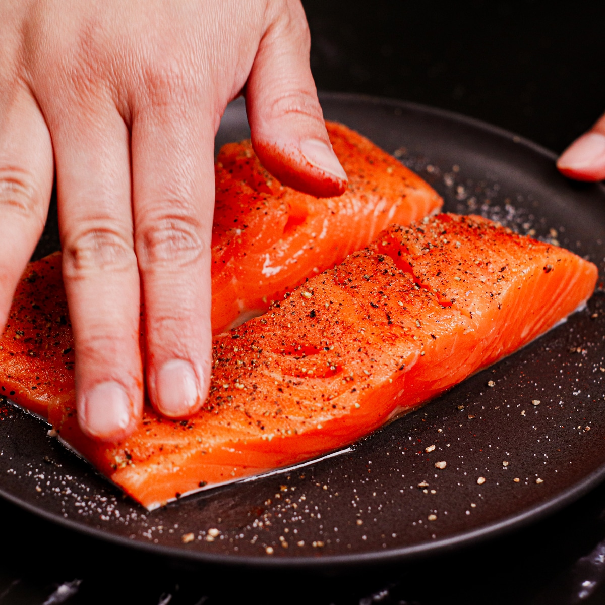 Rubbing salmon filets with paprika, salt and pepper.