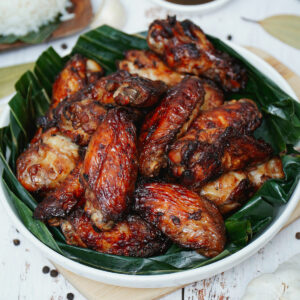 Air fried adobo wings served on a plate with banana leaves.