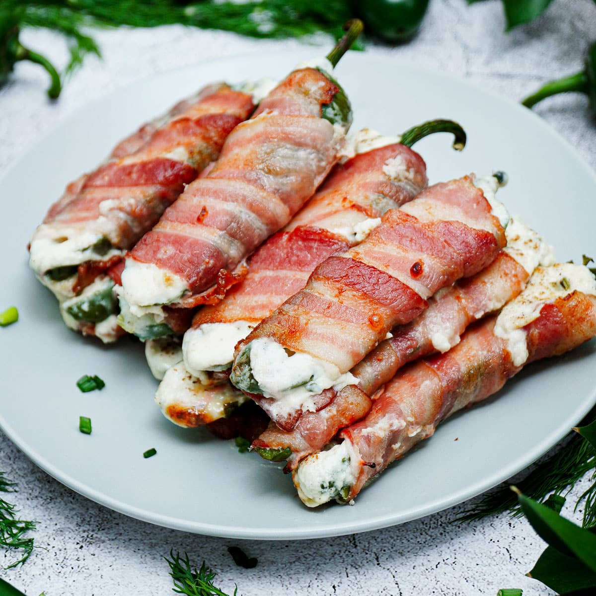 Air fried bacon wrapped jalapeno poppers served on a plate.