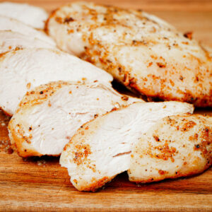 Air fried frozen chicken breast, sliced on a chopping board.