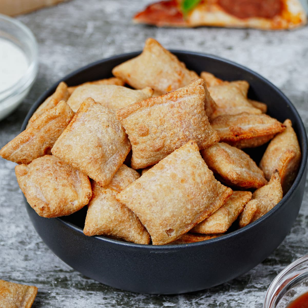 Air fried frozen pizza bites in a black bowl.