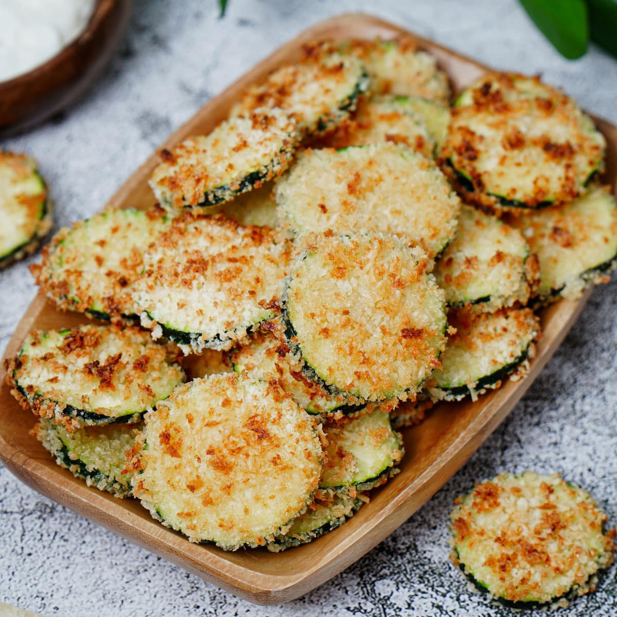 Air fried zucchini chips in a small wooden tray.