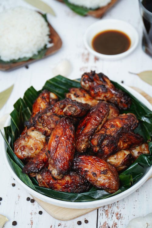 Air fryer adobo chicken wings recipe bite shot, served on a plate with banana leaf.