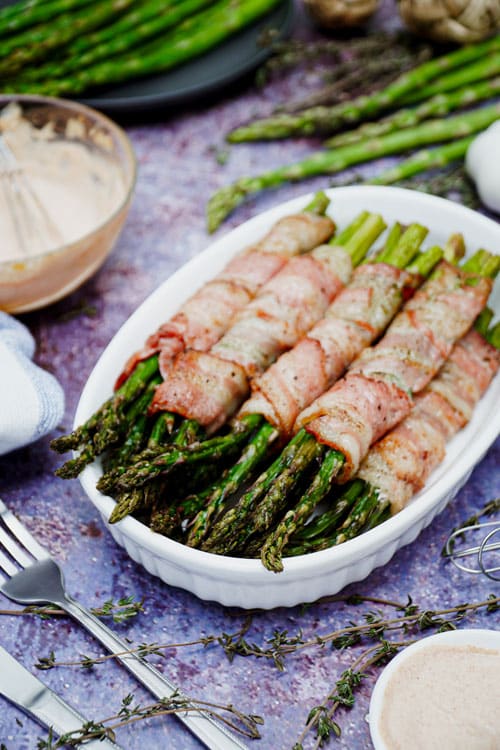 Air fryer bacon wrapped asparagus recipe bite shot, served on a medium-sized baking dish.
