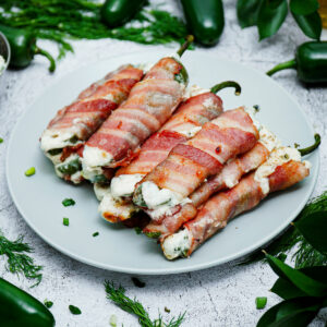 Air fryer bacon wrapped jalapeno poppers served on a plate.