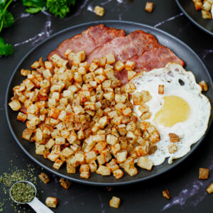 Air fryer home fries with a sunny-side-up and turkey bacon.