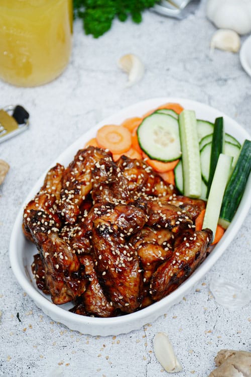 Air fryer teriyaki chicken wings recipe bite shot with carrots and celery sticks.