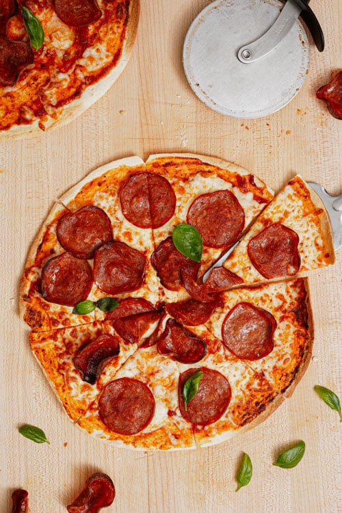 Air Fryer Tortilla Pizza recipe bite shot, with one whole pepperoni pizza cut into eight slices.