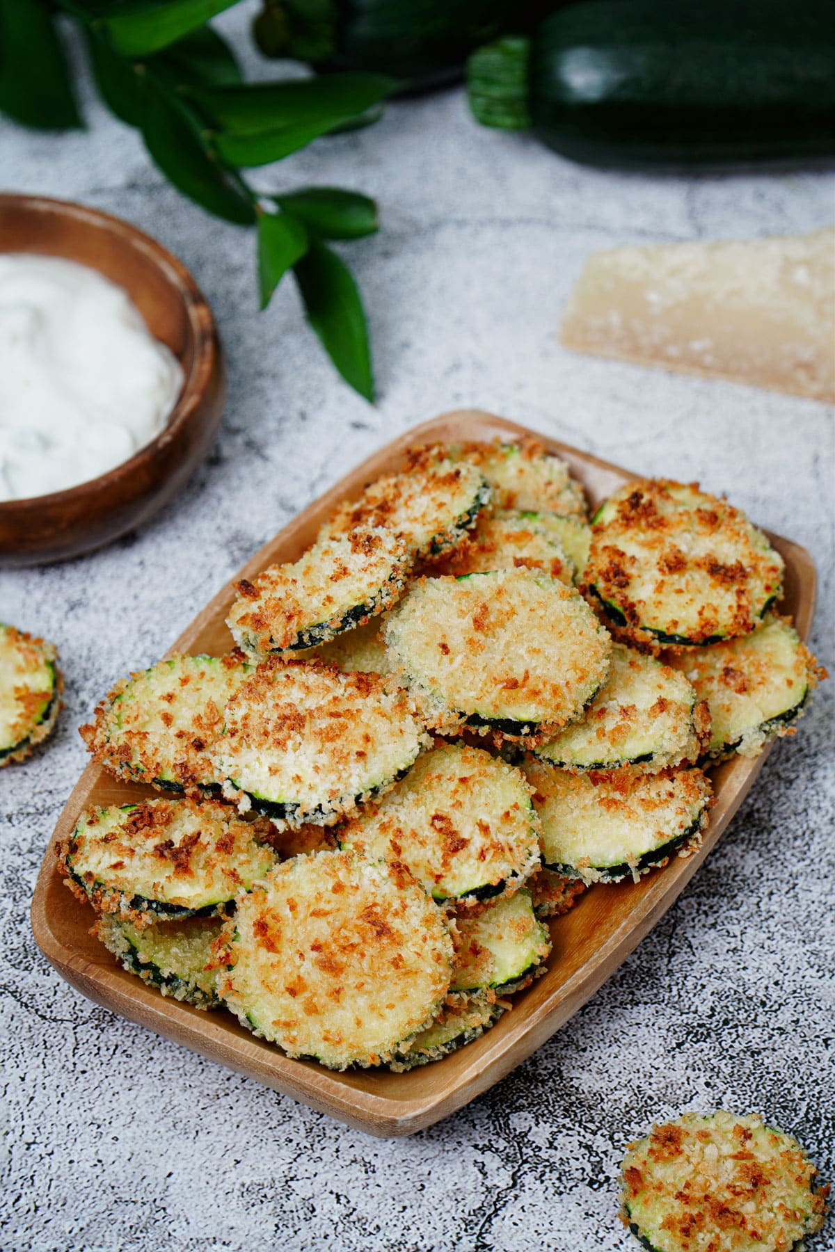 Air fryer zucchini crisps recipe bite shot, served on a small wooden tray.