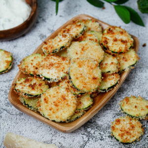 Air fryer zucchini crisps served on a small wooden tray.