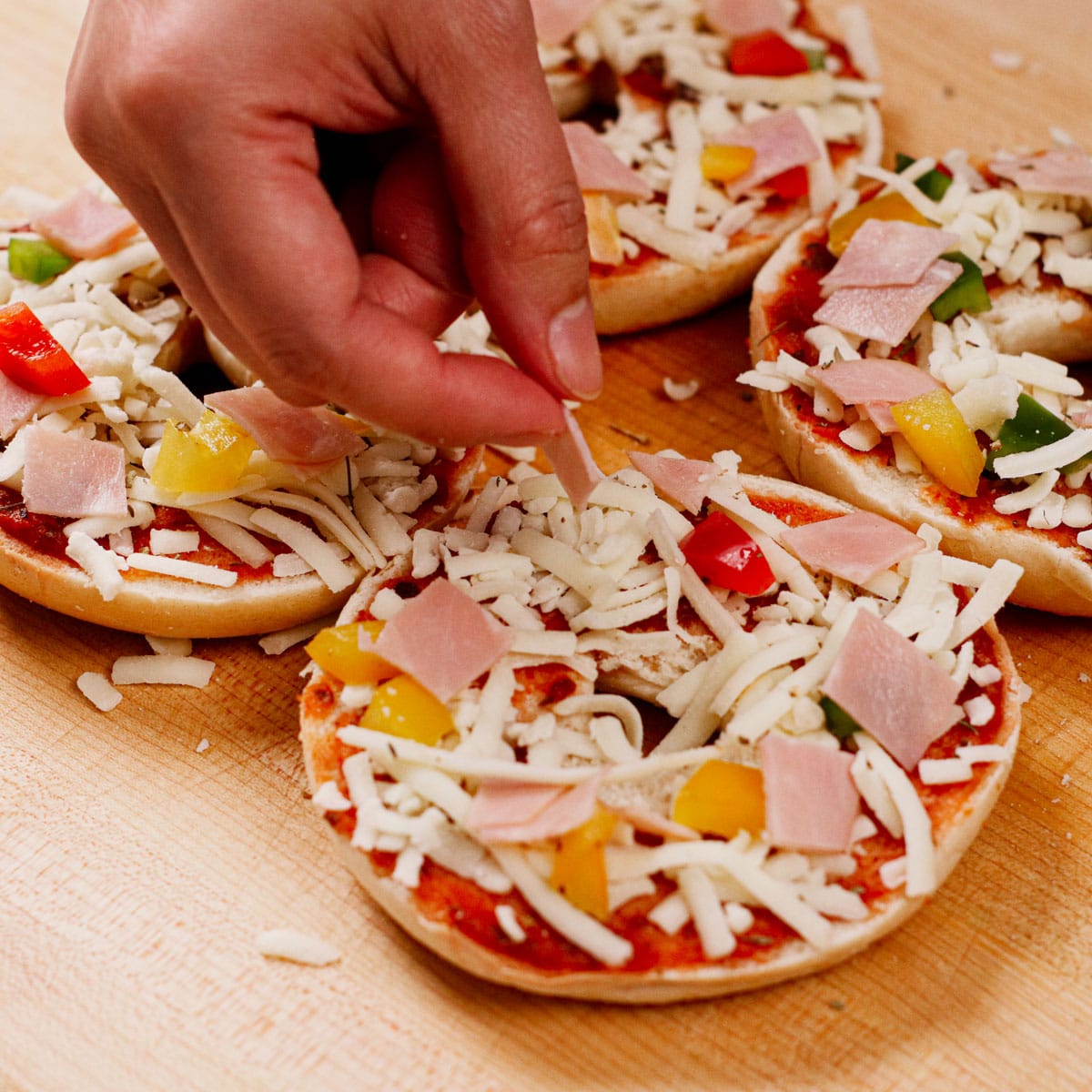 Adding toppings to pizza bagels