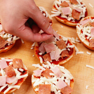 Adding toppings to mini bagel pizza