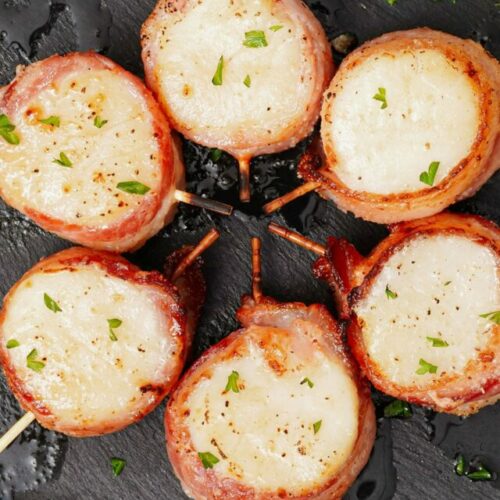 Air Fryer Bacon Wrapped Scallops served with lemon wedges and garnished with parsley