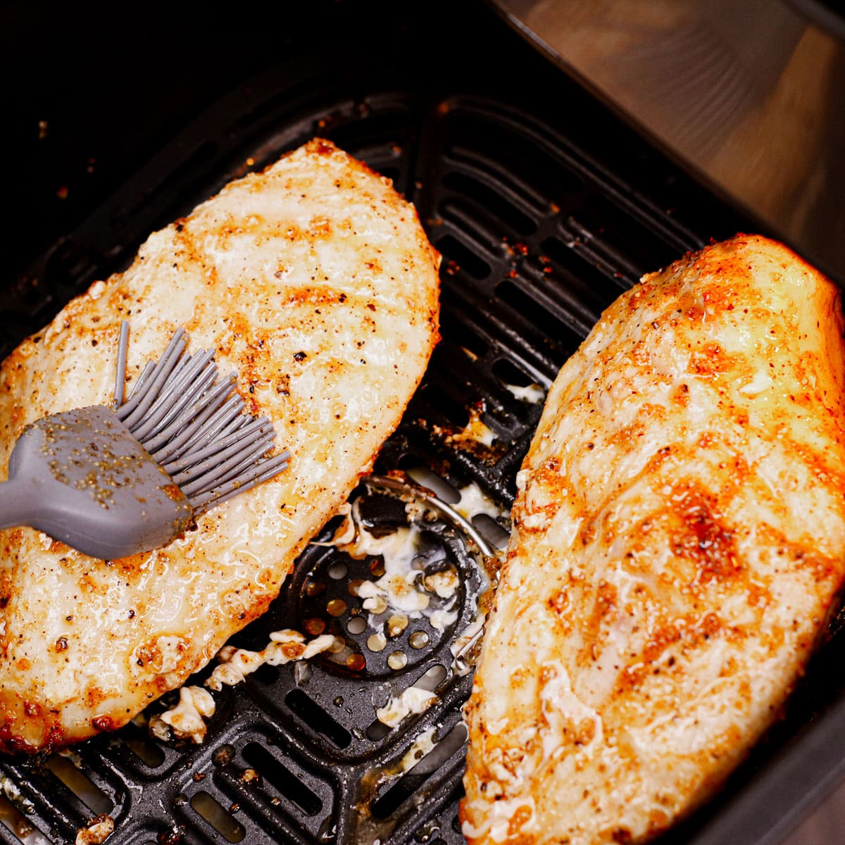 Cooking frozen chicken breast in the air fryer: applying basting sauce.