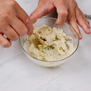 Mixing garlic spread in a small bowl.