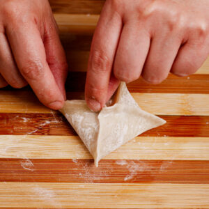 Step 5: Pinching the sides to seal the wonton wrapper.