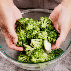 Seasoning broccoli with olive oil, garlic, salt and pepper