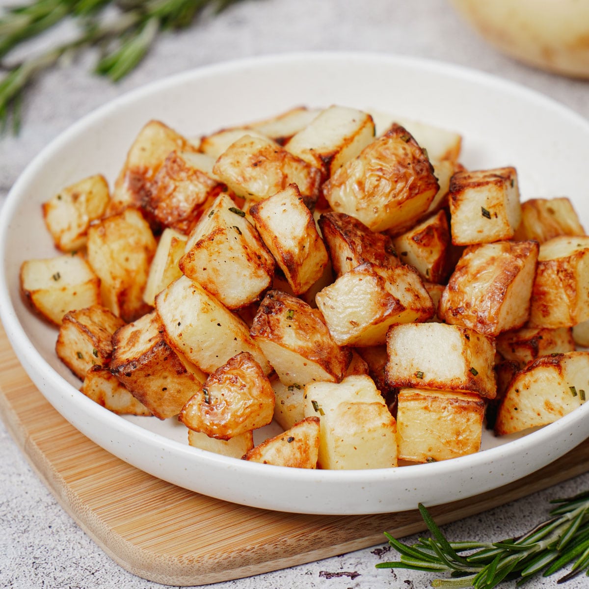 Air fried diced potatoes in a white salad plate.