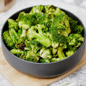 Air fried frozen broccoli in a black bowl.