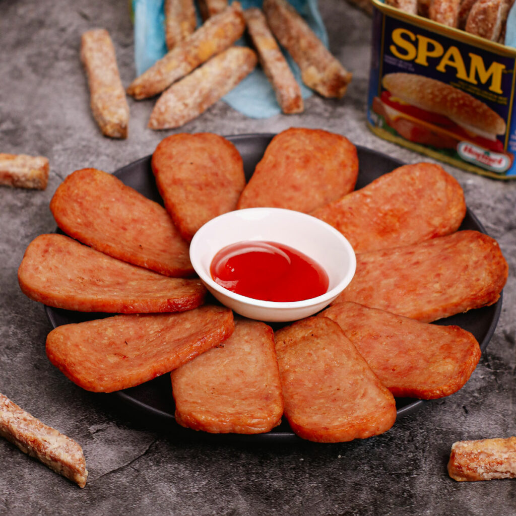 Air fried spam served on a black plate with ketchup.