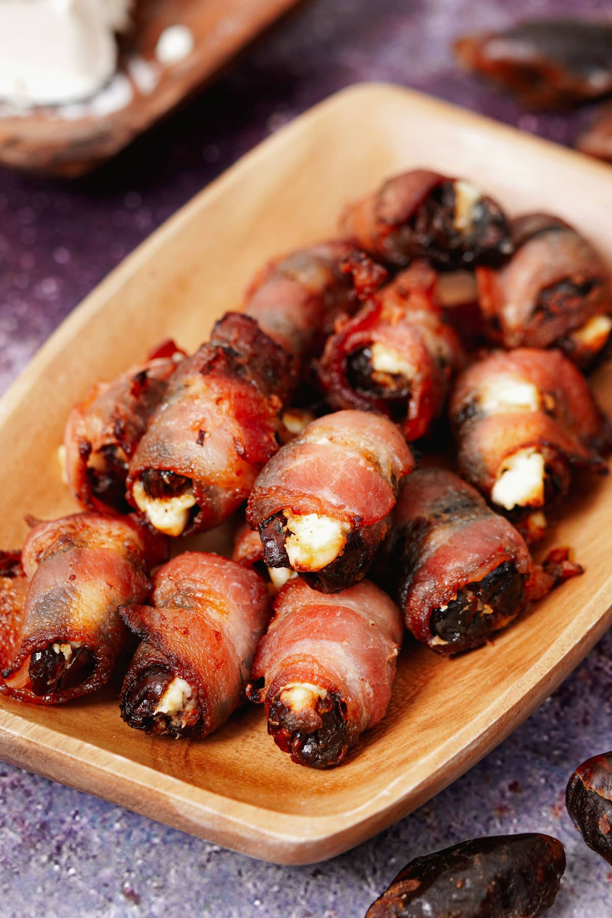Air fryer bacon wrapped dates recipe bite shot in a small wooden tray.