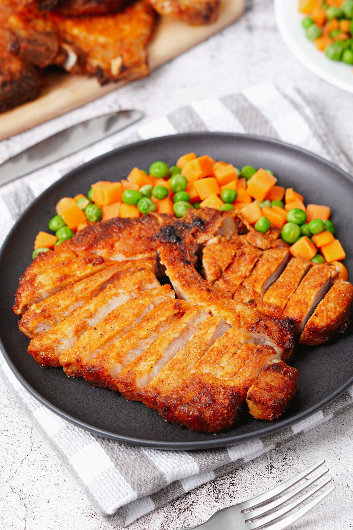 Air fryer bone-in pork chops recipe bite shot, with peas and carrots.