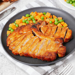 Air fryer bone-in pork chops with peas and diced carrots.