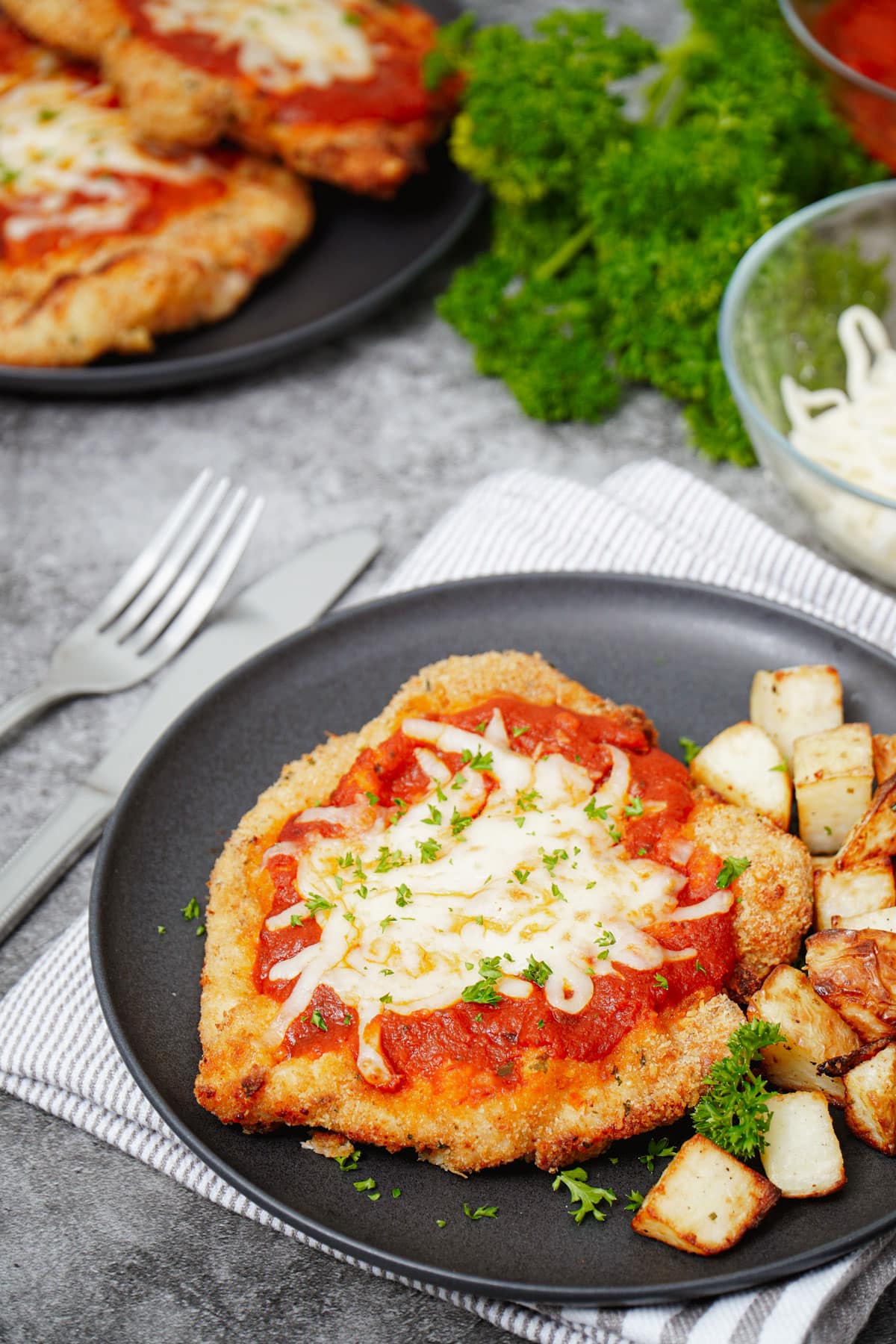 Air fryer chicken parmesan recipe bite shot, served with diced potatoes.