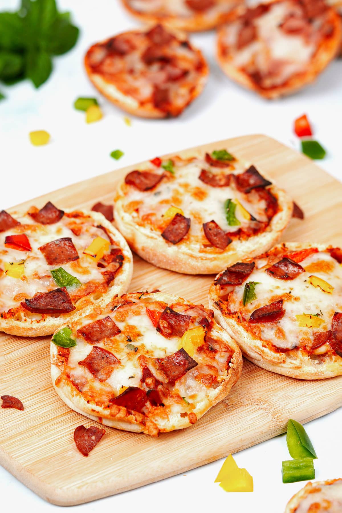 Air fryer English muffin pizza recibe bite shot, 4 slices on a bamboo chopping board.