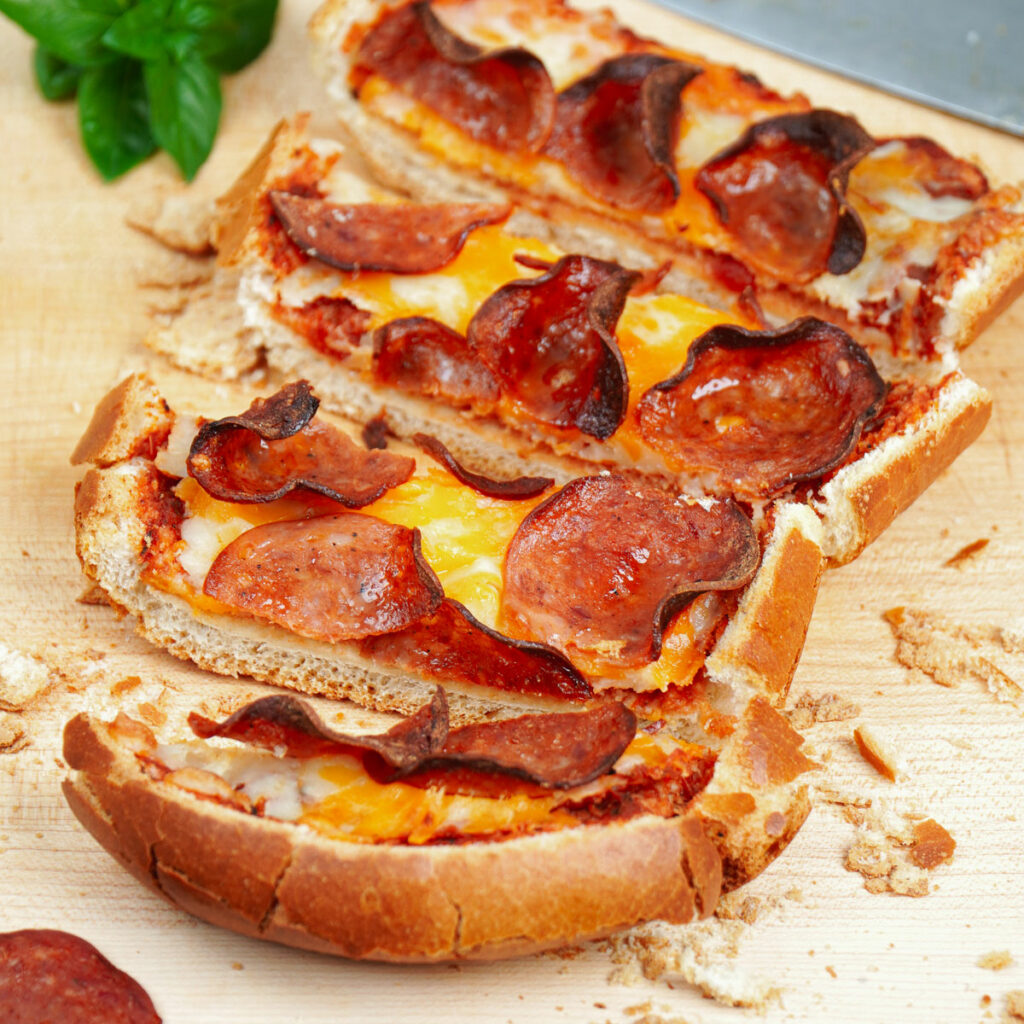 Four slices Air fryer French bread pizza on a chopping board.