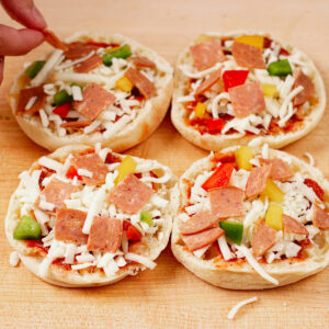 Adding toppings to English muffin pizzas