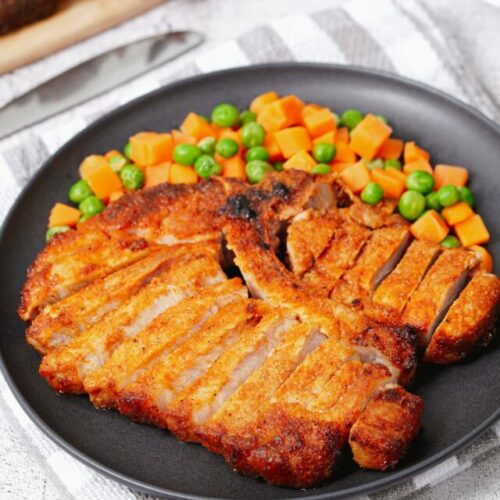 Air fryer bone-in pork chops recipe bite shot, with peas and carrots.