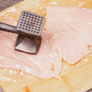 Flattening the chicken breast filets with a mallet.