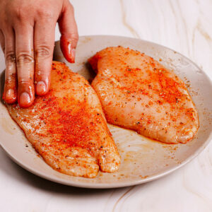 Seasoning chicken breast filets with dry rub mixture.