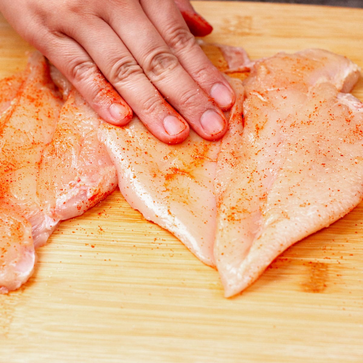 Seasoning chicken breast with paprika and salt