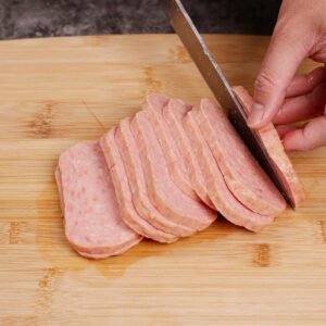 Cutting SPAM meatloaf into 1/4-inch thick slices