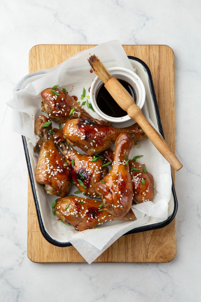 Air fryer keto chicken drumsticks, recipe bite-shot, topped with sesame seeds and scallions